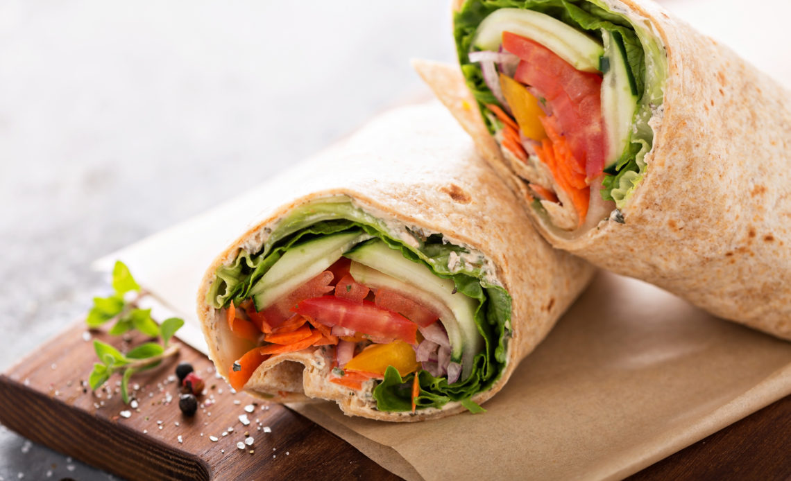 Vegan vegetable wrap with lettuce, cucumber and tomatoes sliced in half